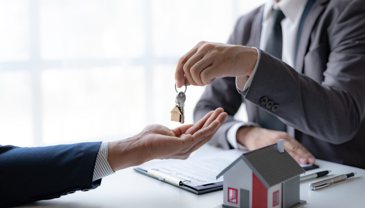A professional real estate agent is giving house keys to a client during a property sale transaction.