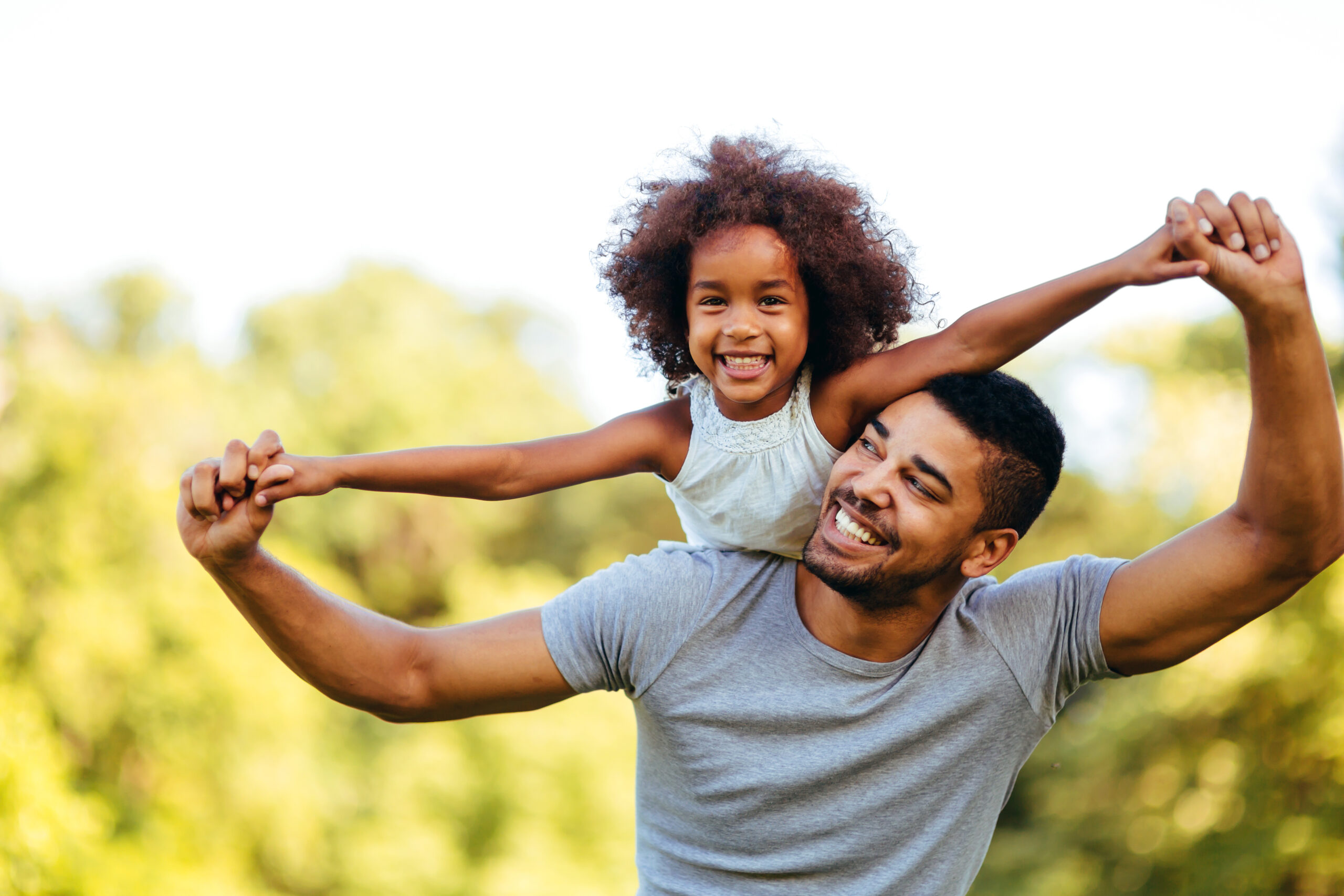 Portrait of young father carrying his daughter on his back