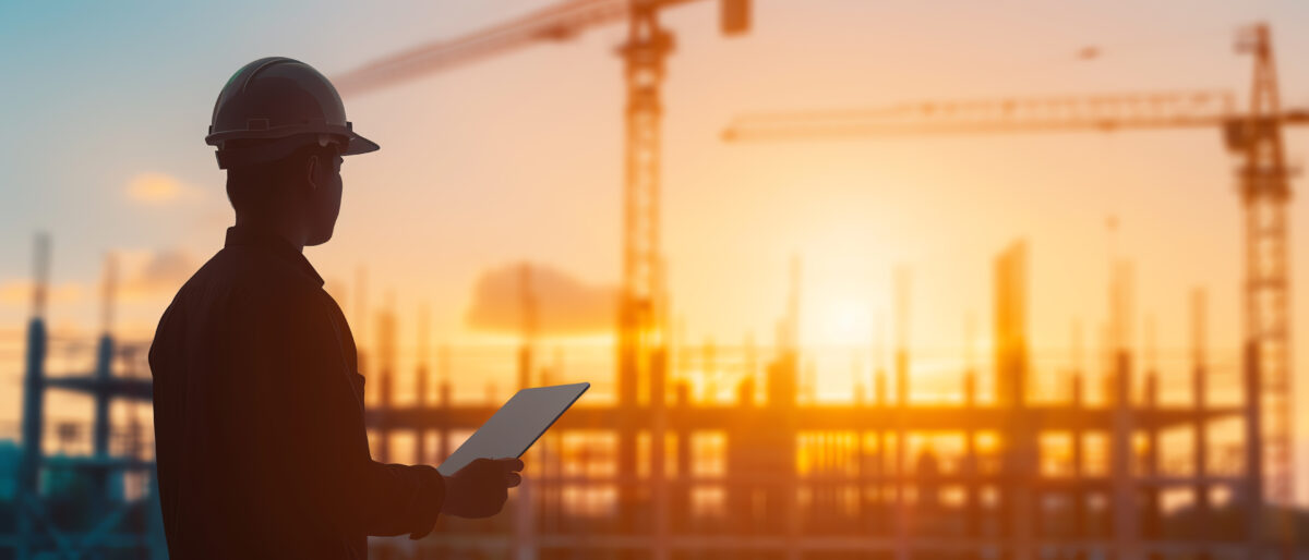 Project manager using a tablet to check construction progress, with the site in the background